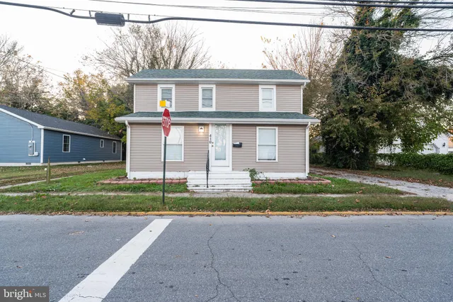 a view of a house with a yard and a large tree