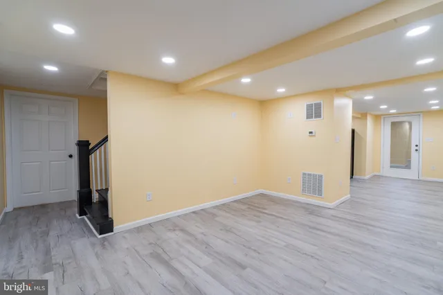 an empty room with wooden floor and a hallway
