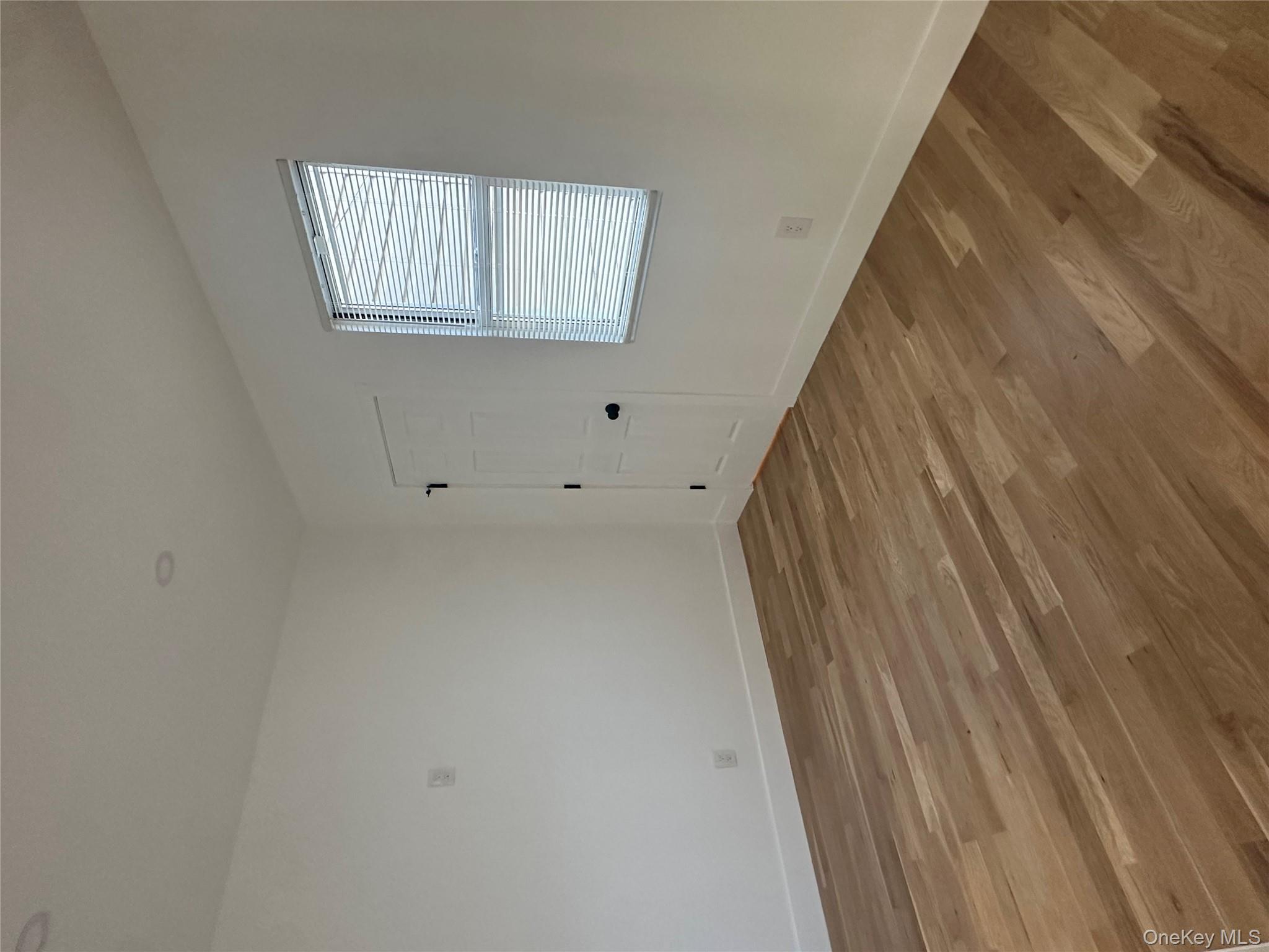 Undisclosed Address Queens, NY 11416 - Photo 4 of 10 an empty room with wooden floor and windows