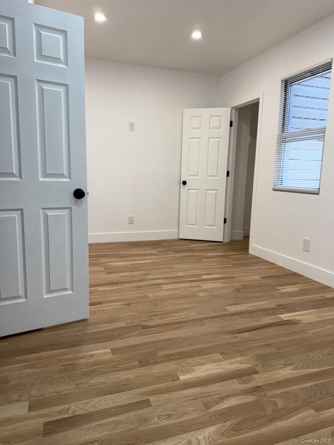 Undisclosed Address Queens, NY 11416 - Photo 6 of 10 a view of an empty room with wooden floor and entryway