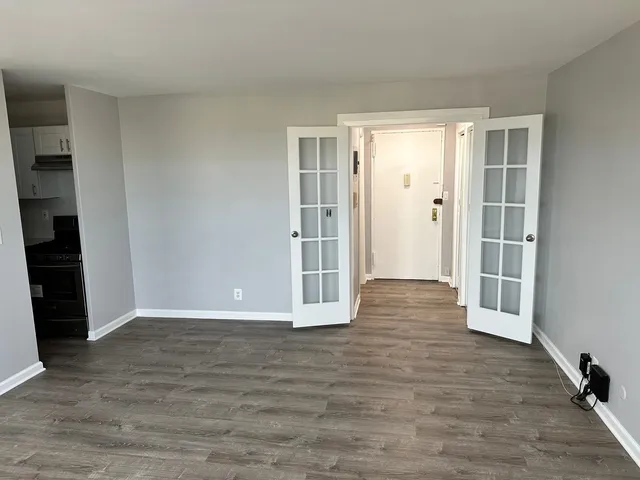 a view of an empty room with wooden floor and stairs