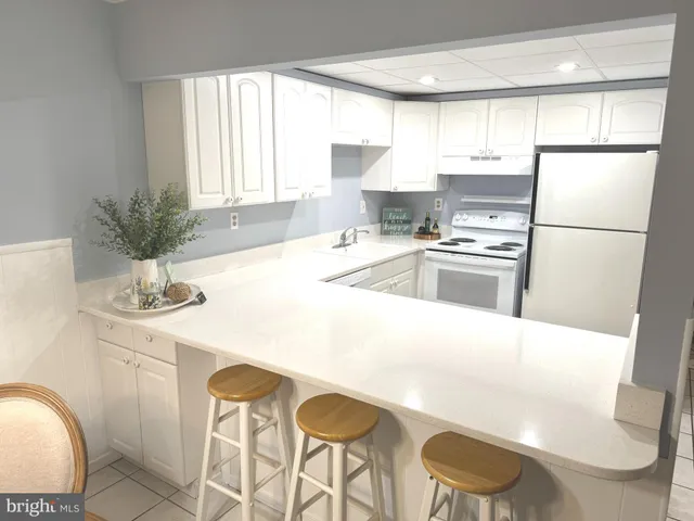 a kitchen with stainless steel appliances a refrigerator a sink a stove a table and chairs