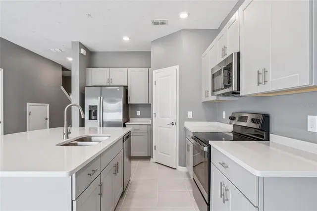 a kitchen with kitchen island white cabinets stainless steel appliances and sink