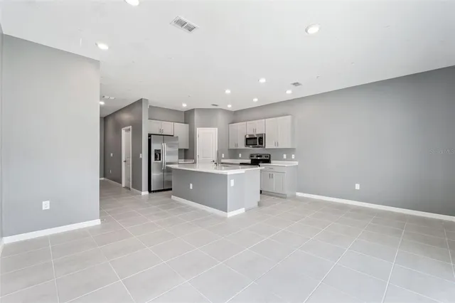 a large kitchen with a refrigerator and white cabinets