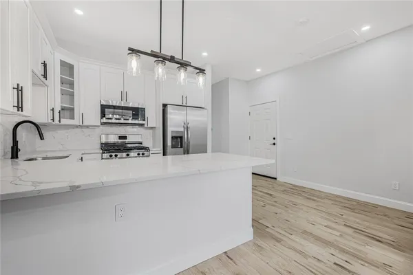 a view of a kitchen with stainless steel appliances a center island wooden floor and a chandelier