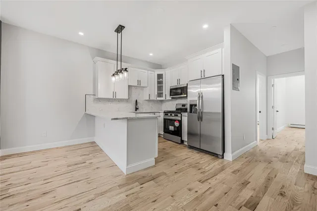 a view of kitchen with stainless steel appliances granite countertop a stove a sink and a refrigerator with wooden floors