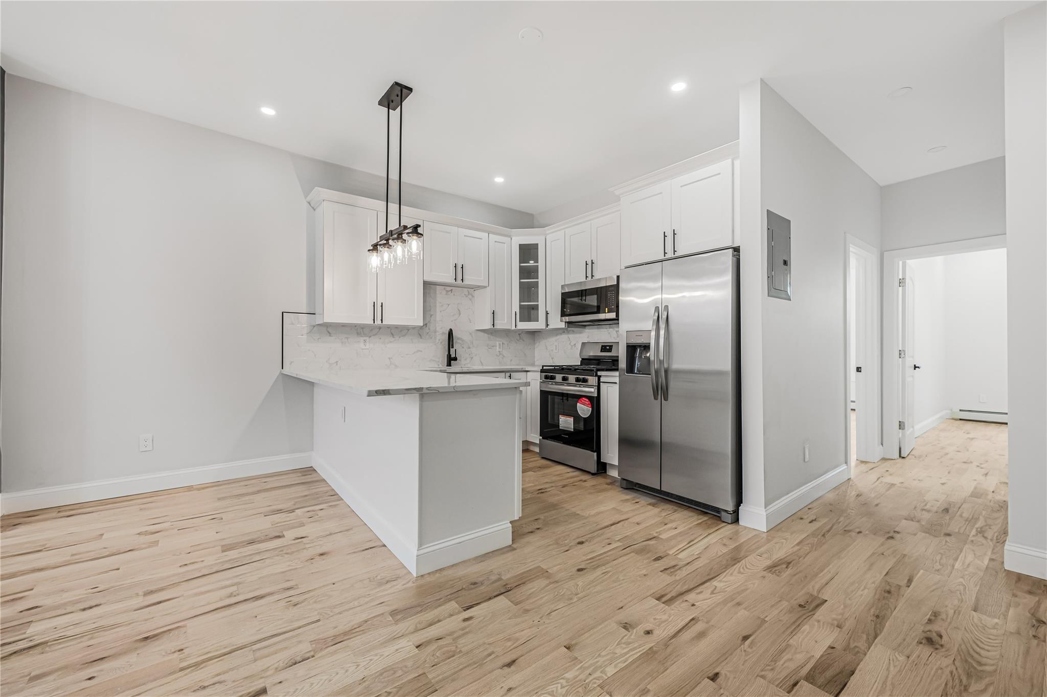 164 Atkins Avenue, Unit 2 Brooklyn, NY 11208 - Photo 22 of 23 a kitchen with kitchen island white cabinets and stainless steel appliances