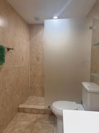 a white toilet sitting next to a shower