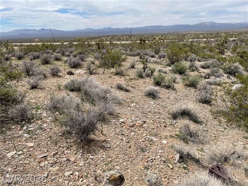 95 Us Searchlight, NV 89046 - Photo 2 of 6 A vast, rugged desert landscape unfolds, framed by distant mountains under a broad sky.