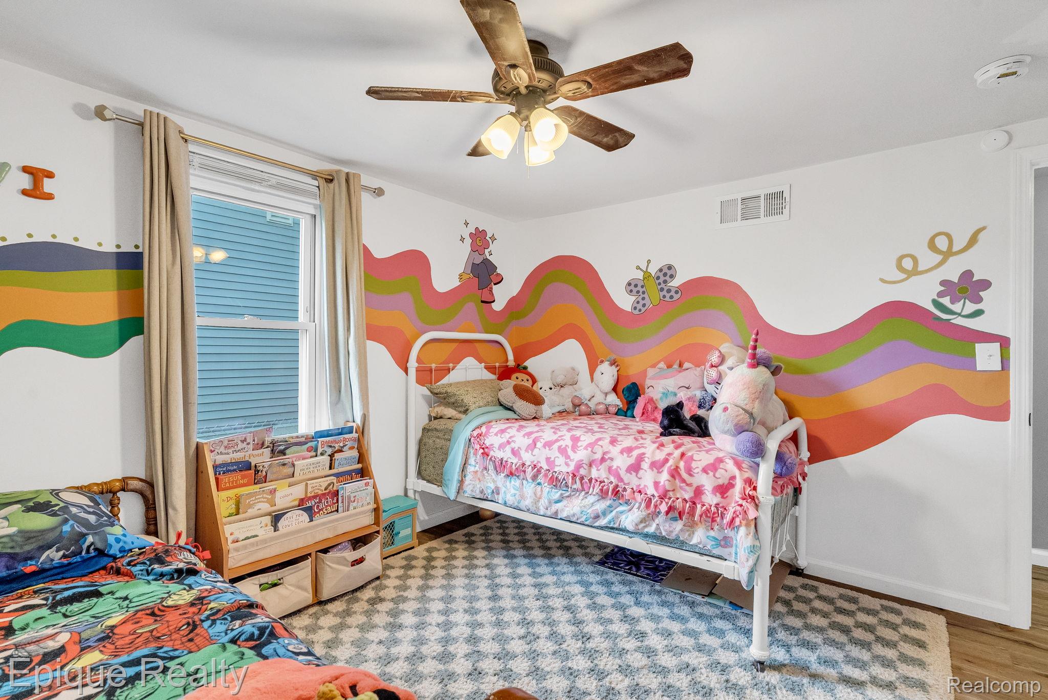 2182 North Center Road Burton, MI 48509 - Photo 26 of 34 White walls featuring colorful wave patterns, a wood-finish ceiling fan with integrated lighting, and a single window with light-colored drapes