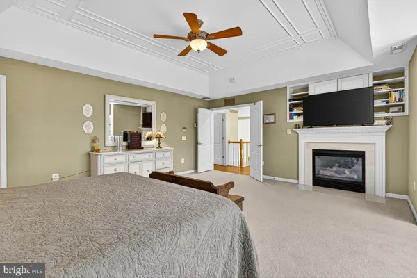 a spacious bedroom with a large bed a flat screen tv and a fireplace
