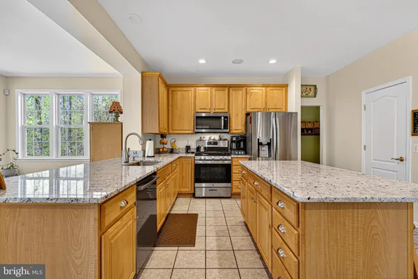a large kitchen with stainless steel appliances granite countertop a stove a sink and a refrigerator