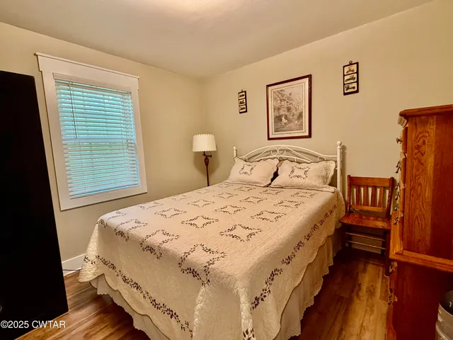 a bedroom with a bed next to a window with wooden floor