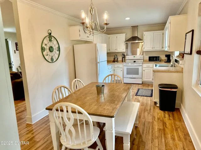 a large kitchen with stainless steel appliances granite countertop a dining table chairs and a refrigerator