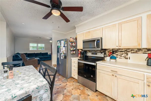 a kitchen with stainless steel appliances kitchen island granite countertop a stove top oven a sink a counter space and cabinets