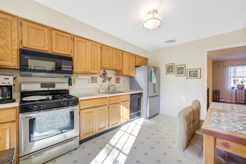 68 Colgate Avenue Paramus, NJ 07652 - Photo 7 of 14 a kitchen with stainless steel appliances granite countertop a stove top oven a sink dishwasher a dining table and chairs with wooden floor