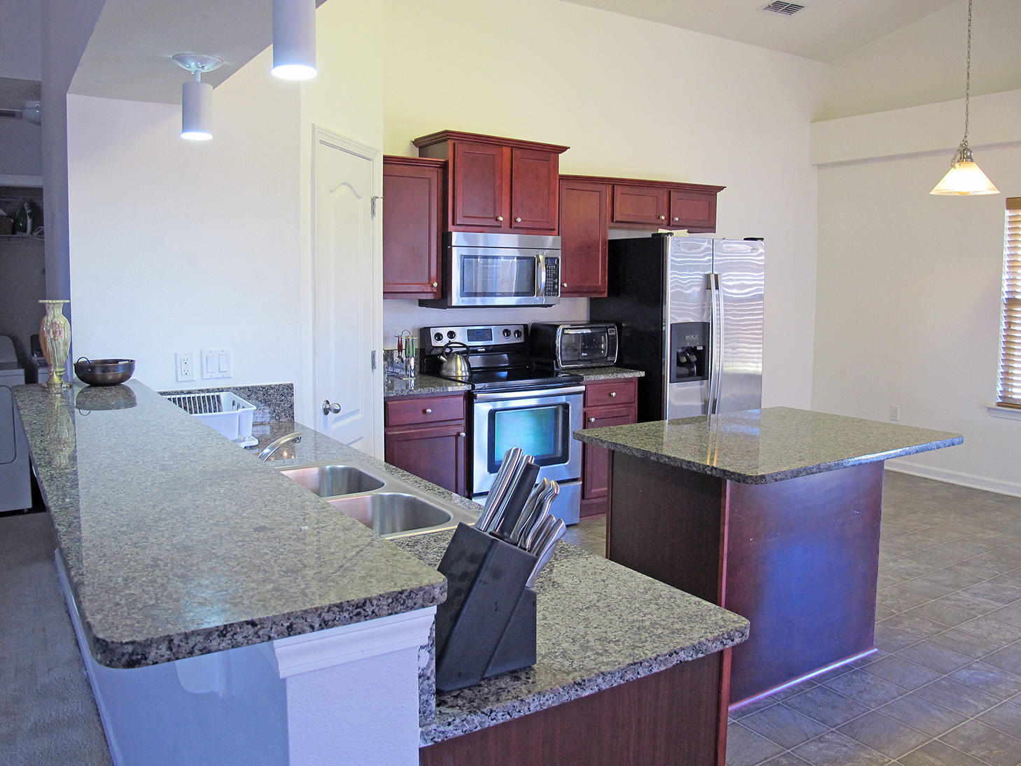 7980 Promise Creek Road Navarre, FL 32566 - Photo 11 of 31 a kitchen with kitchen island granite countertop a sink a stove and refrigerator