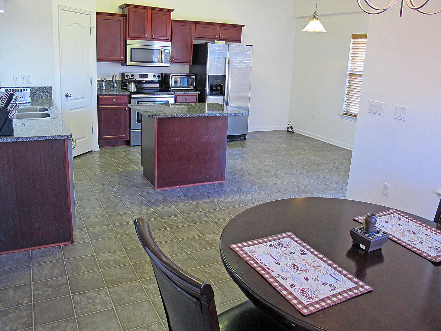 7980 Promise Creek Road Navarre, FL 32566 - Photo 14 of 31 a kitchen with stainless steel appliances kitchen island granite countertop a stove a sink and a refrigerator
