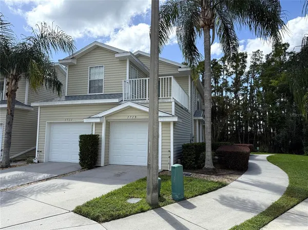 a front view of a house with a yard and palm trees