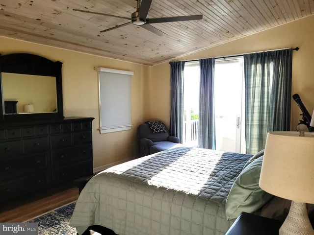 a bedroom with a bed a dresser and a large window