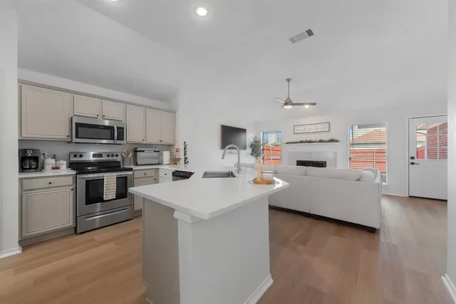 a kitchen with granite countertop a sink a counter top space and stainless steel appliances