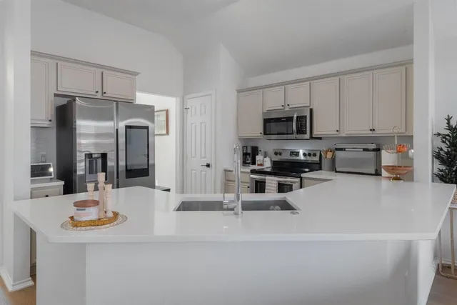 a kitchen with stainless steel appliances a stove a sink a refrigerator a microwave and cabinets