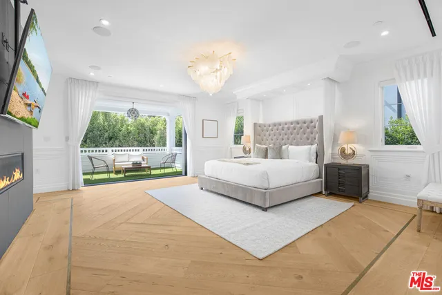 a bedroom with a large bed and a flat tv screen on dresser