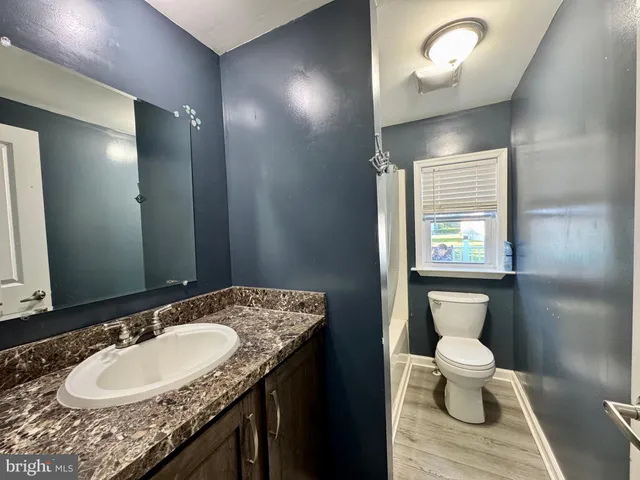 a bathroom with a granite countertop sink a toilet and a mirror
