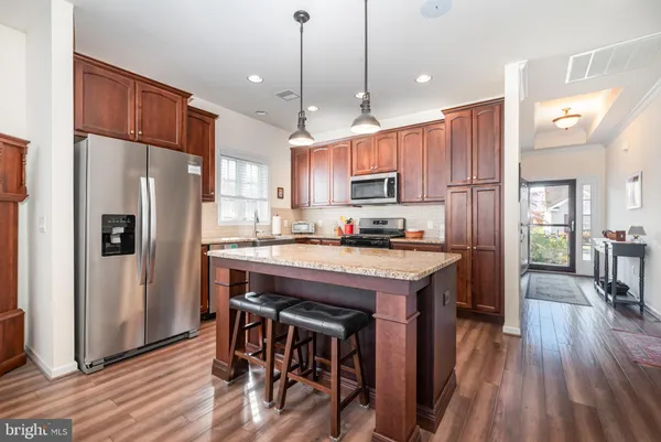 a kitchen with kitchen island a refrigerator a stove a sink and a dining table with wooden floor