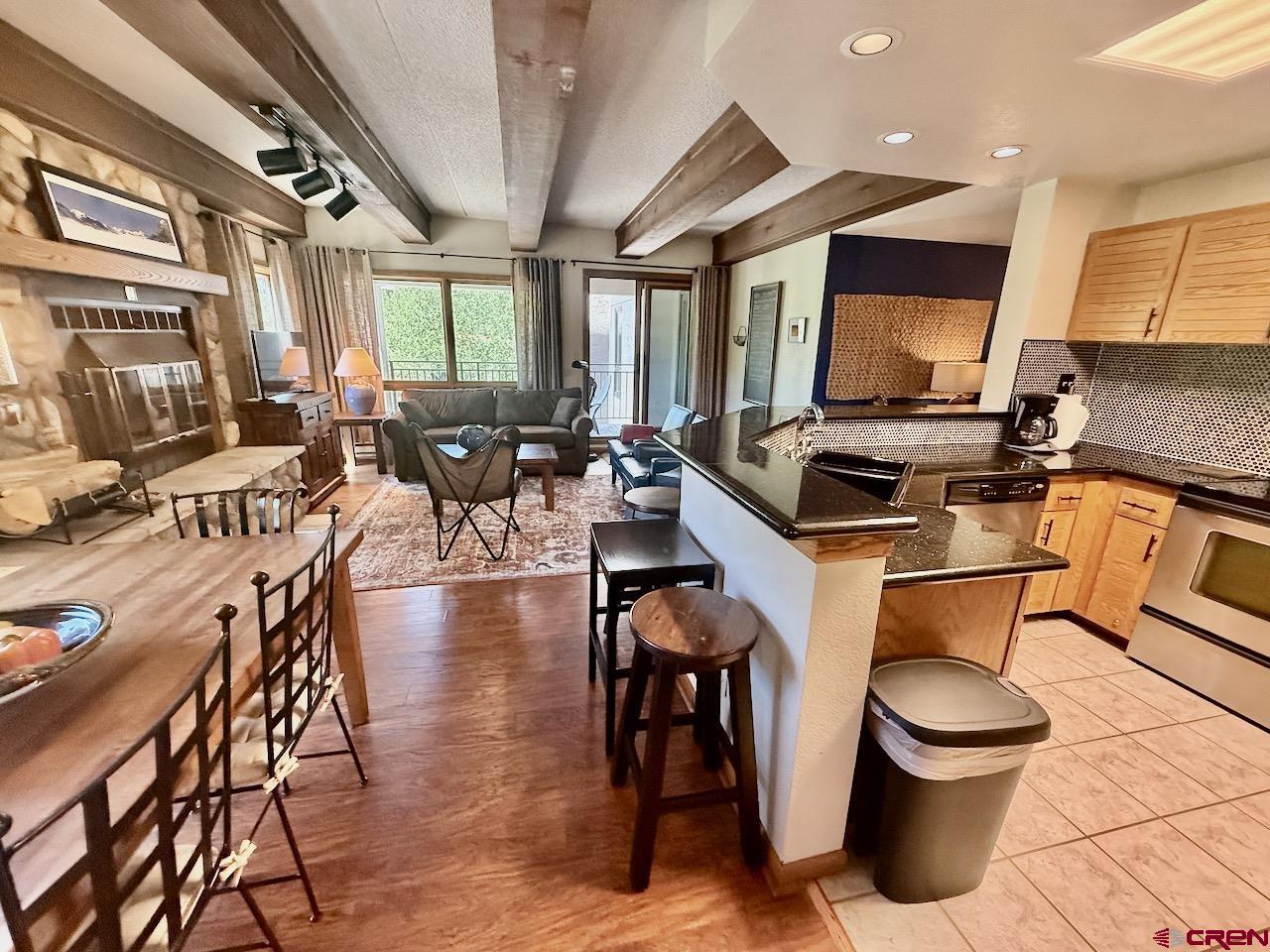 11 Snowmass Road, Unit 337 Crested Butte, CO 81225 - Photo 11 of 35 a kitchen with stainless steel appliances a stove a sink a dining table and chairs with wooden floor