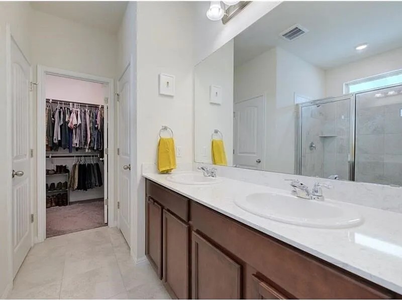 167 Iron Rail Road Dripping Springs, TX 78620 - Photo 12 of 17 Bathroom with a stall shower, double vanity, a spacious closet, and tile patterned floors