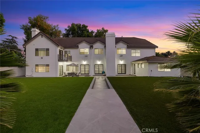 a front view of a house with a garden and trees