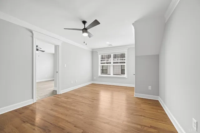 a view of empty room with wooden floor and ceiling fan