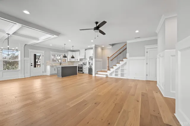 an empty room with wooden floor a ceiling fan and windows
