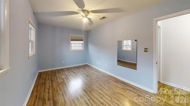 an empty room with wooden floor a fireplace and windows