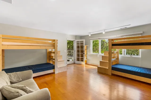 a view of a livingroom with furniture a fireplace wooden floor and windows