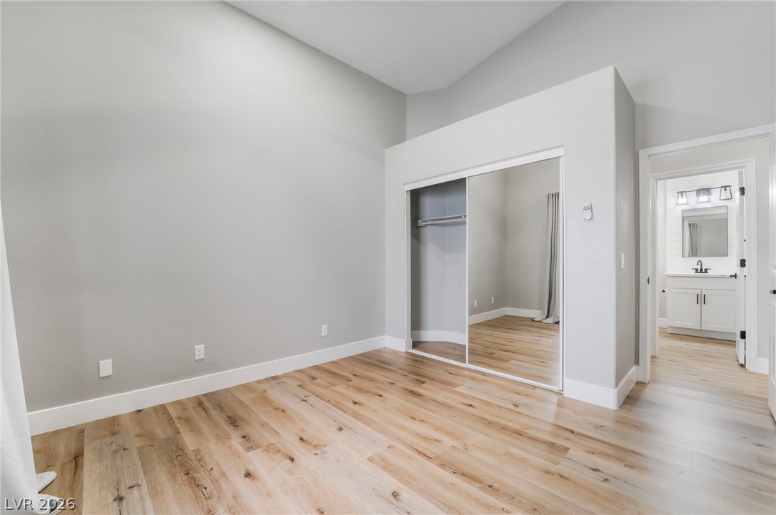 9171 West Viking Road Las Vegas, NV 89147 - Photo 29 of 43 Natural-toned flooring extends throughout this peaceful bedroom, featuring a mirrored closet and vaulted ceilings.