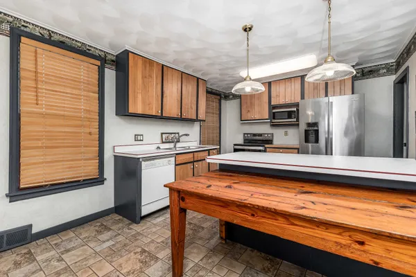 a kitchen with stainless steel appliances granite countertop a refrigerator a sink dishwasher a stove and white cabinets with wooden floor