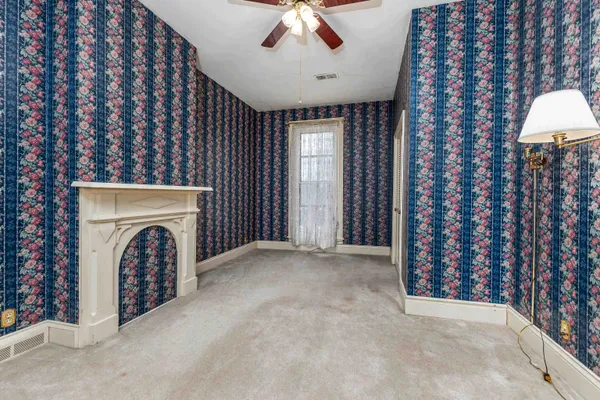 a view of an empty room with a fireplace and a chandelier fan