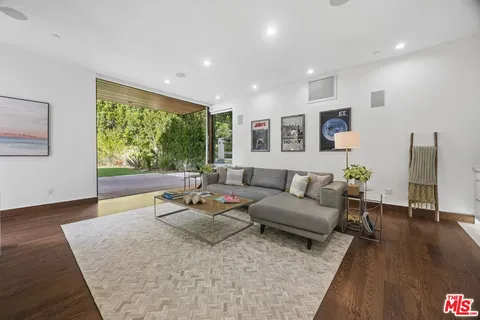a dining hall with stainless steel appliances kitchen island granite countertop a table chairs and a view of living room