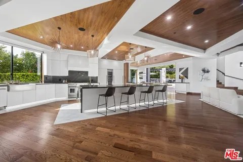 a large white kitchen with lots of counter space and stainless steel appliances