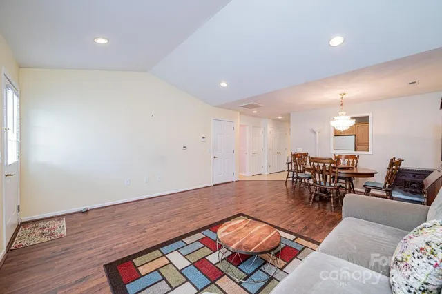 a living room with furniture and a dining table with wooden floor