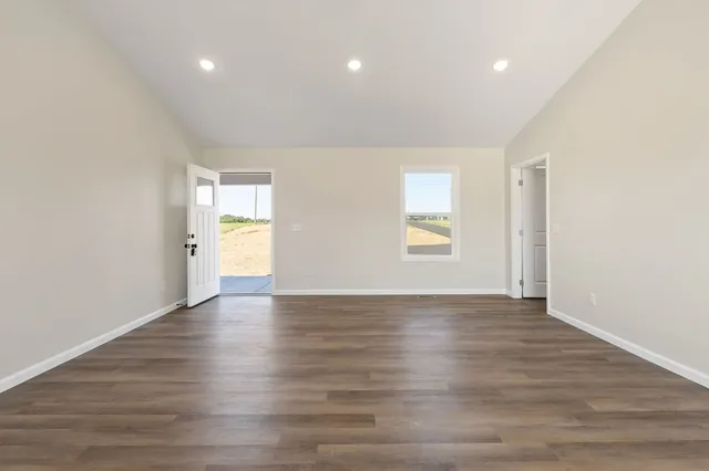 a view of an empty room with window and wooden floor