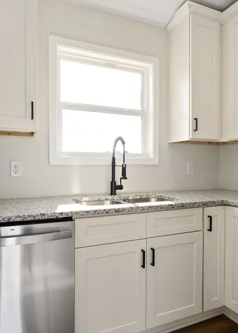 a kitchen with granite countertop a sink white cabinets and a window