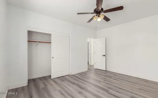 an empty room with wooden floor ceiling fan and window