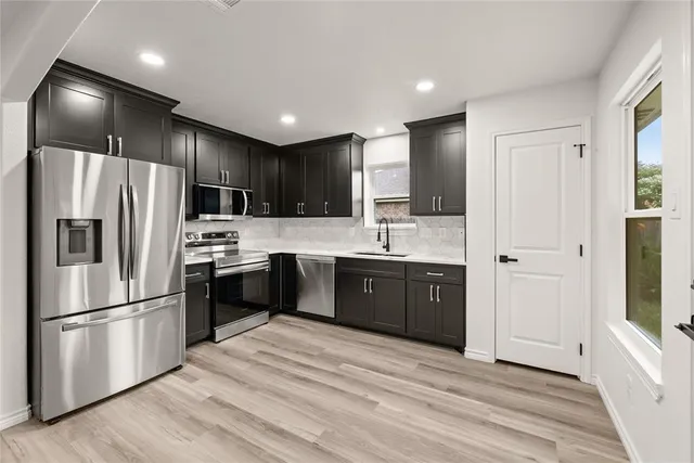 a kitchen with stainless steel appliances kitchen island granite countertop a refrigerator a sink a stove and a oven