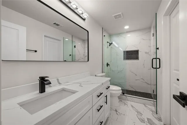 a bathroom with a sink a toilet and shower