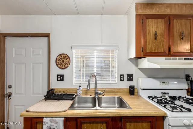 a kitchen with a sink and a stove with wooden floor