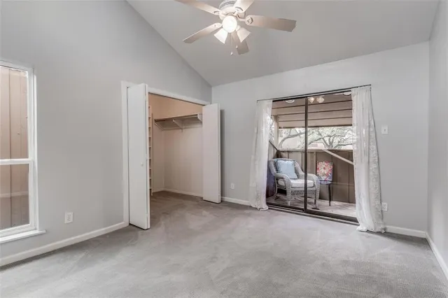an empty room with chandelier fan and windows