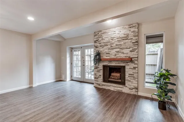 an empty room with wooden floor fireplace and windows